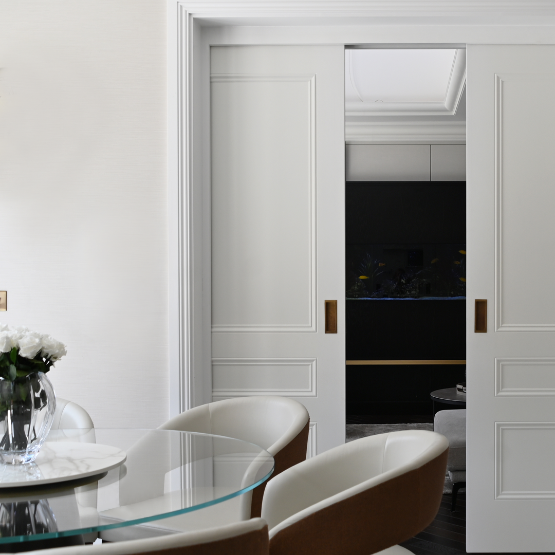 Dining area with panelled sliding doors opening to a dark kitchen