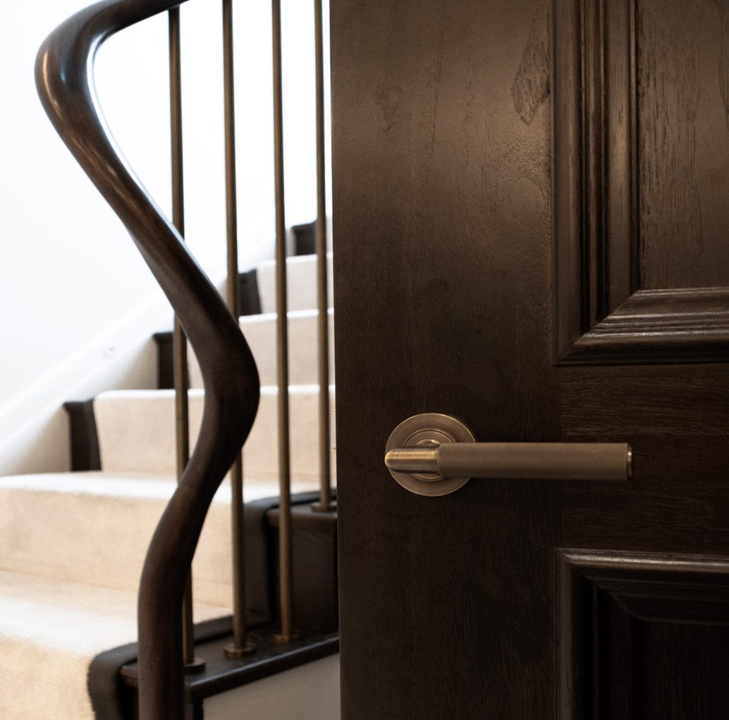 Organically formed handrail beside a dark timber door